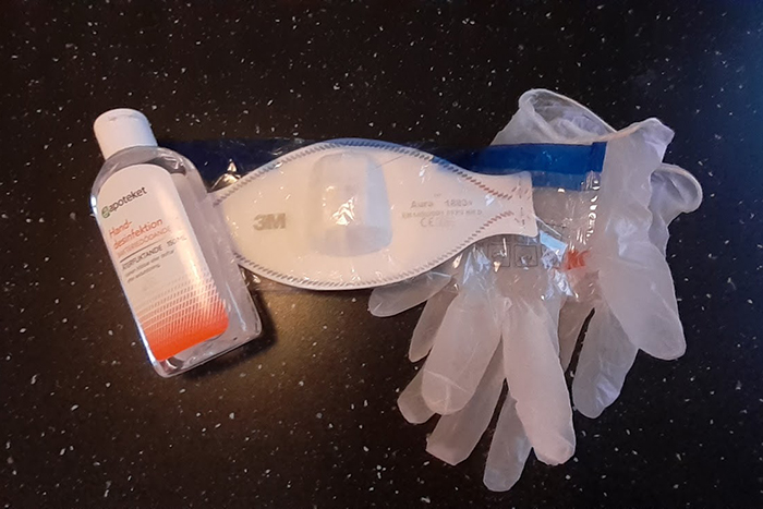 Foto på bland annat handsprit och skyddshandskar som ligger på ett bord.