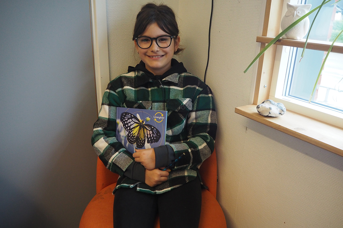 Tea som håller i en bok om fjärilar.